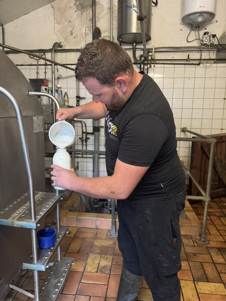 Valentijn zapft frische Milch aus dem Tank in eine Flasche