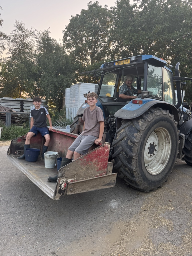 Zwei Teenager auf dem Frontlader des Traktors, Opa Henk in der Kabine